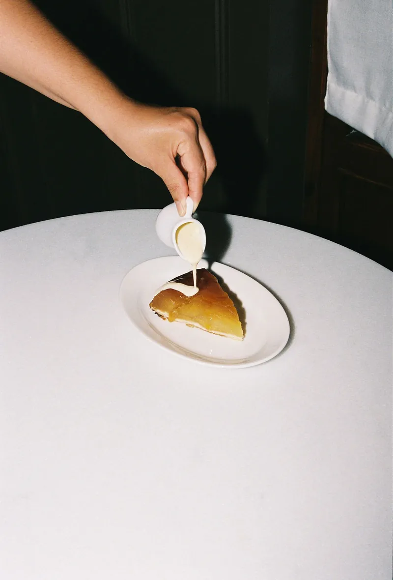 Una mà aboca crema sobre un postre, a la taula