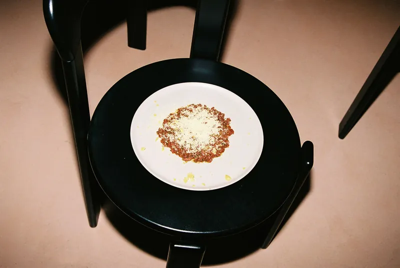 Un plat de carn picada amb formatge ratllat, sobre el seient d’una cadira